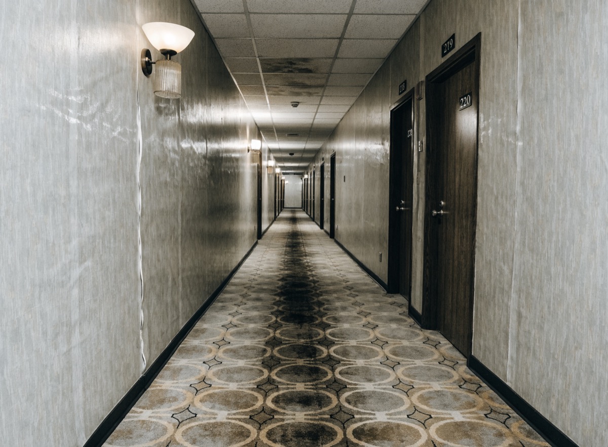 Hotel corridor with traffic-lane soiling on patterned carpet and seam separation in the vinyl wallcovering.